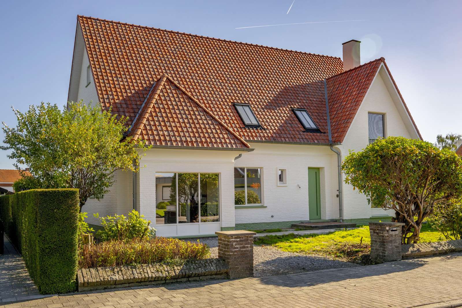 Witte woning met een hellend dak in rode pannen